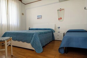Un dormitorio con dos camas, una mesita de noche, una silla y un espejo montado en la pared.