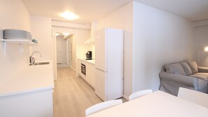 Una cocina moderna con electrodomésticos blancos, un comedor con mesa y sillas, y un sofá en la sala de estar.