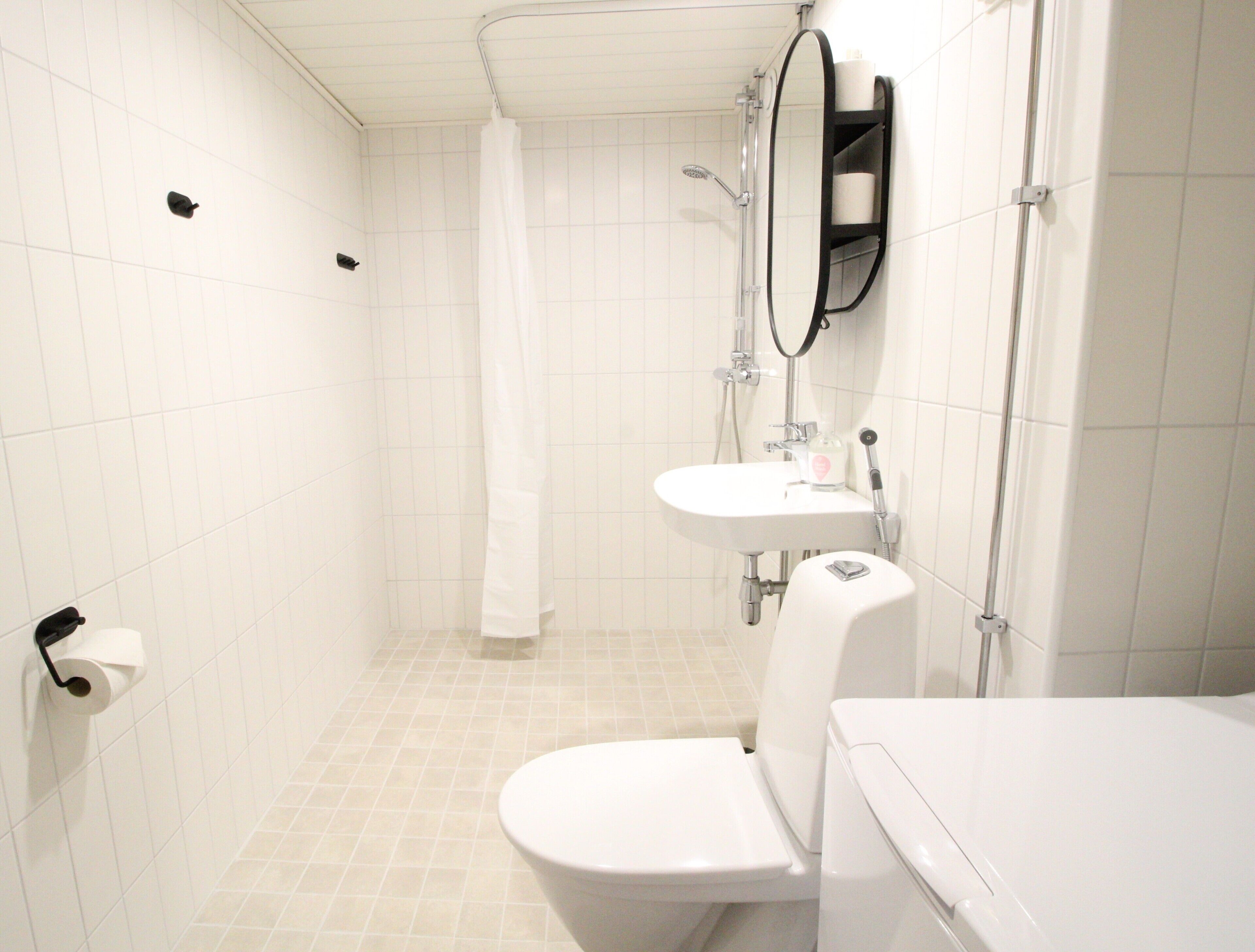 Et badeværelse med toilet, håndvask og bruser.