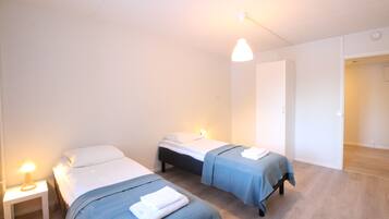 A room with two beds, a nightstand, and a hanging light fixture.