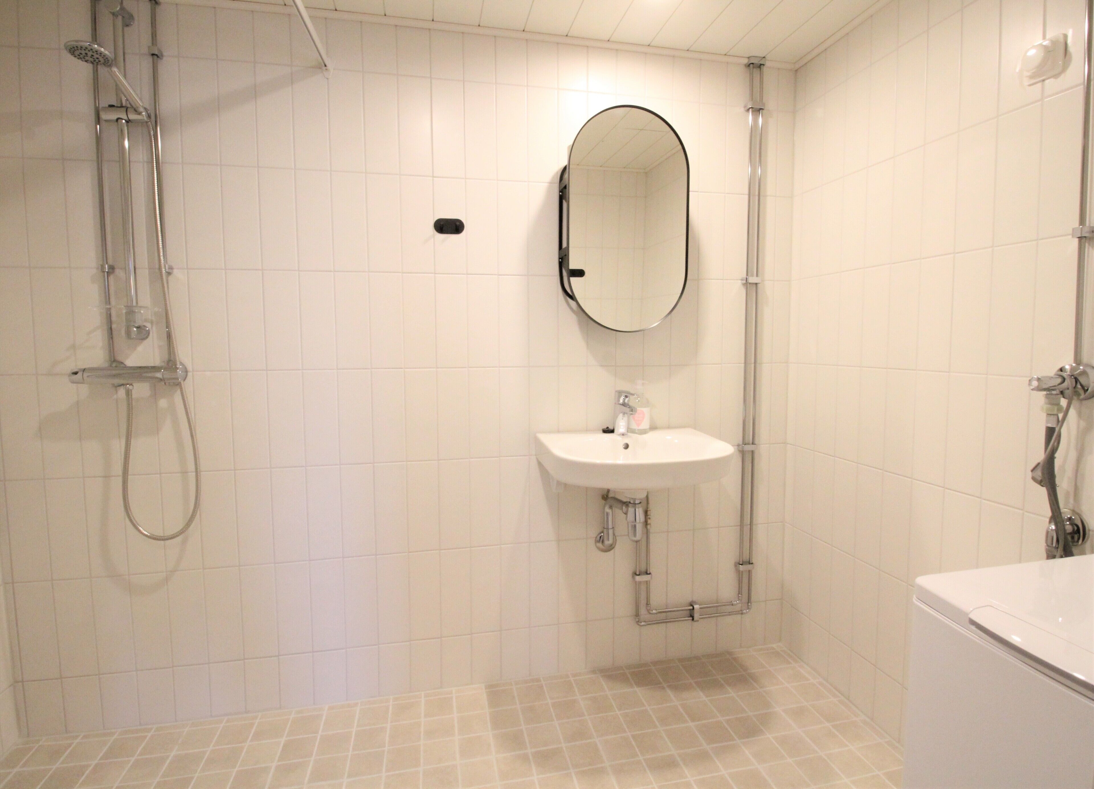 Un baño con ducha, lavamanos y espejo.
