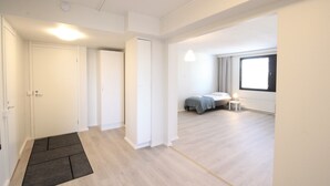Una habitación amplia y luminosa con un gran ventanal, una cama y una mesita de noche.