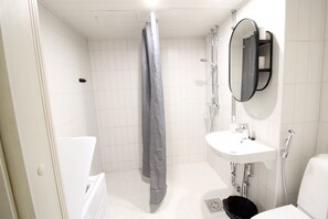 A modern bathroom with a bathtub, shower, sink, and a mirror. - Forenom Apts Hämeenlinna Katuma 3 (Hameenlinna)