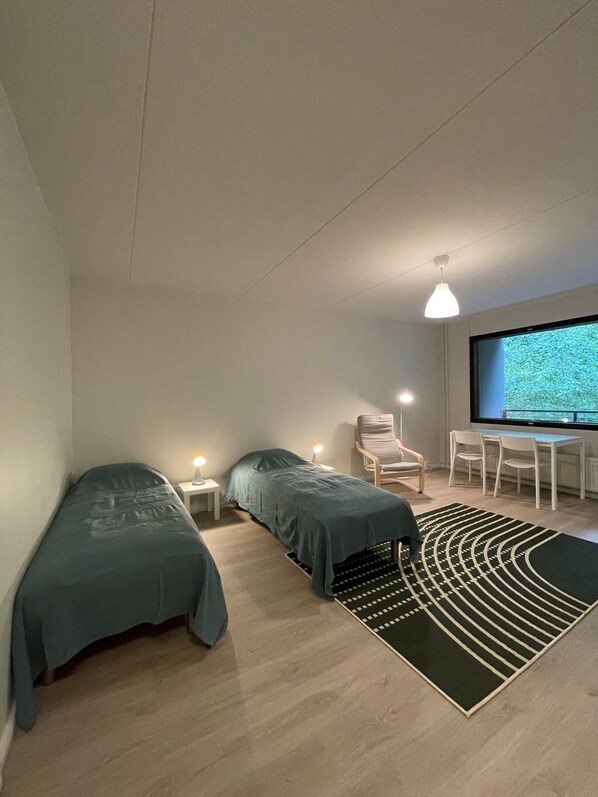 A compact room with two single beds, a desk, a chair, and a large window. - Forenom Apts Hämeenlinna Katuma 3 (Hameenlinna)