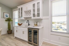 Una cocina con muebles blancos, un refrigerador de acero inoxidable y vistas por la ventana.