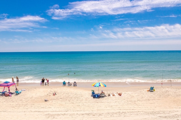 Una playa con gente, sombrillas y sillas de playa.