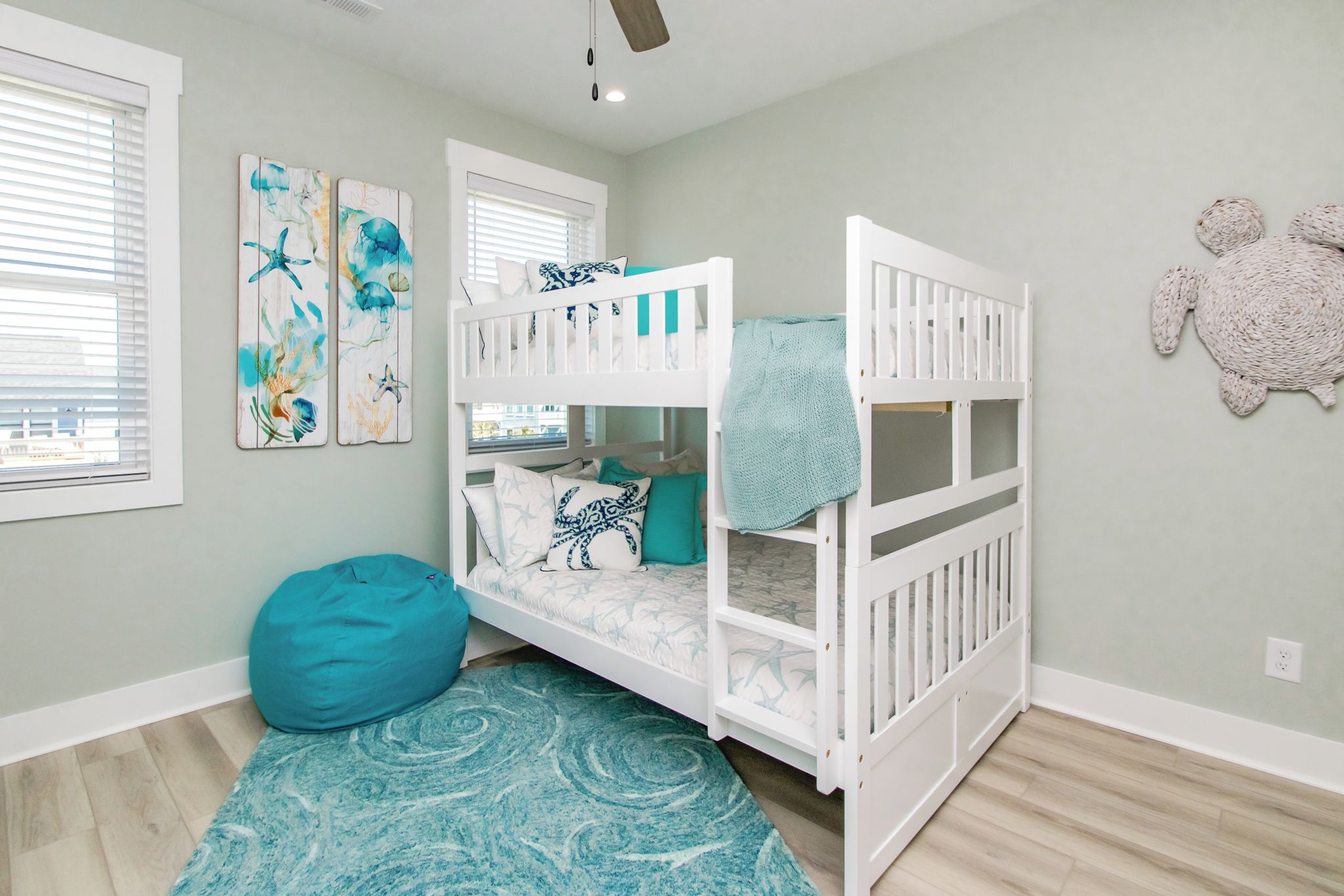 A child's bedroom with bunk beds, a bean bag, and artwork on the wall.