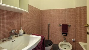 Une salle de bain équipée d’un lavabo, de toilettes, d’un bidet et d’un miroir.
