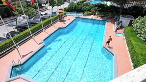 Une piscine rectangulaire à l’eau d’un bleu limpide, entourée d’une terrasse carrelée et d’un petit muret en briques.