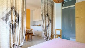 Une chambre à coucher avec un lit, des rideaux, une chaise en bois et une petite table.
