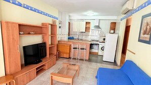 Un espacio habitable compacto con televisión, sofá y kitchenette.