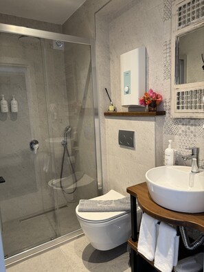 A modern bathroom with a glass-enclosed shower, a white toilet, and a wooden vanity with a sink. - H&R Alaçatı Hotel (Cesme)