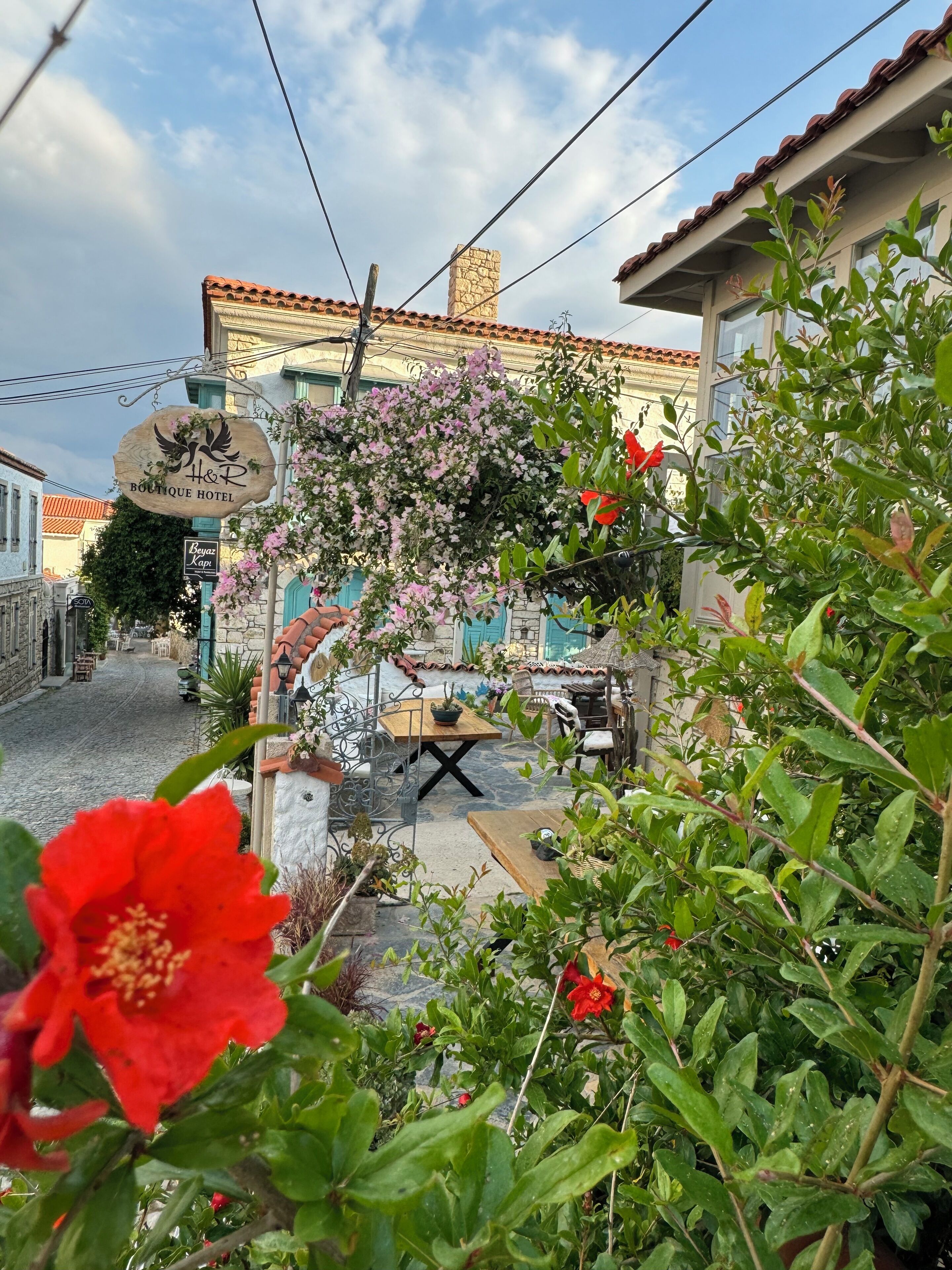 A boutique hotel with a stone facade, outdoor seating area, and a signboard.