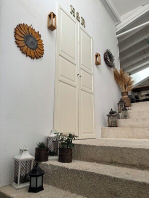 A white door with "H&R" above it, a sunflower decoration, and a staircase with lanterns and plants. - H&R Alaçatı Hotel (Cesme)