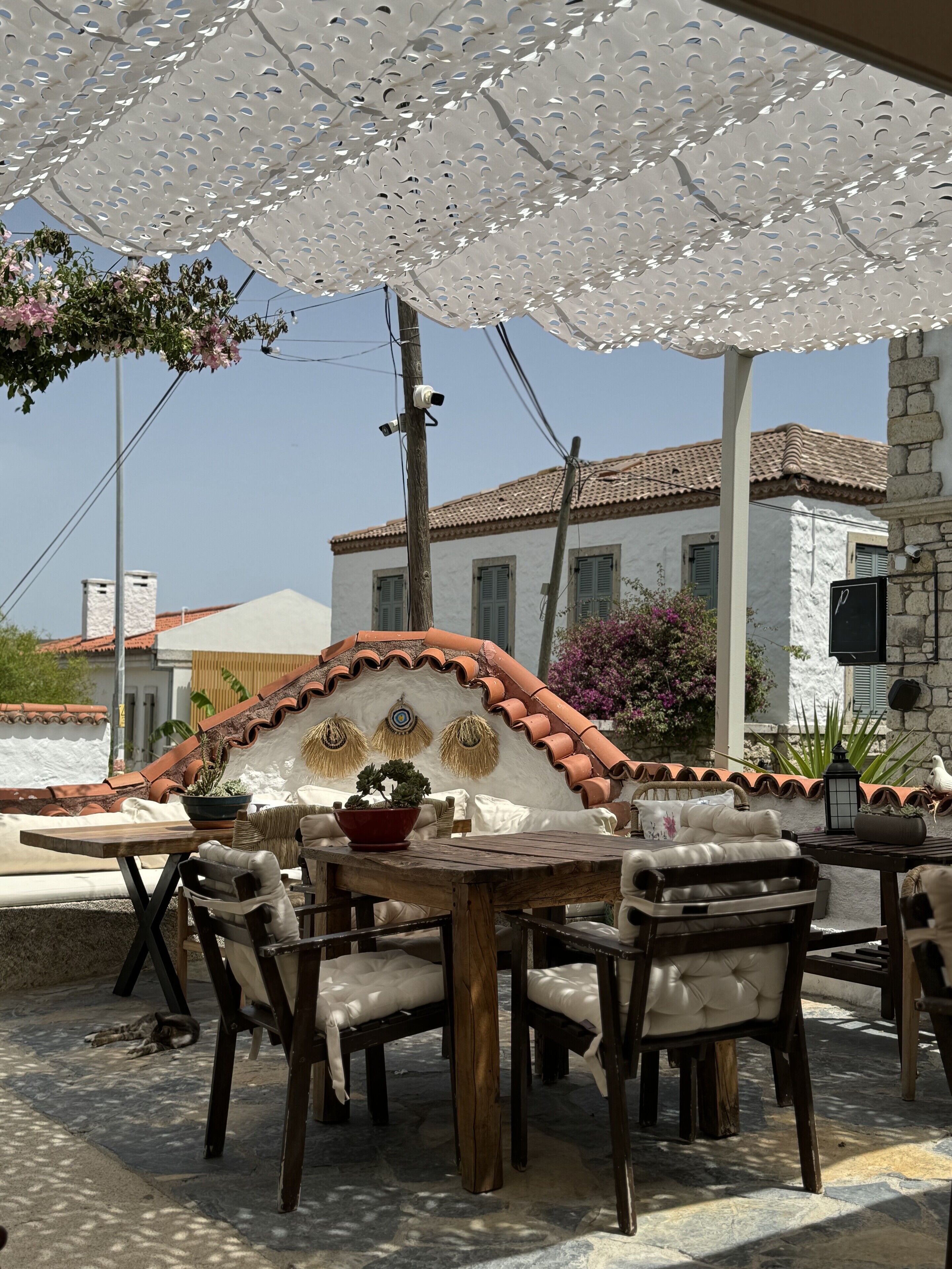 Un espace extérieur aménagé avec une table et des chaises de style rustique, un mur décoratif et une vue sur un bâtiment traditionnel en arrière-plan.