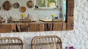 A rustic interior with a wooden dining table, wicker chairs, and a large mirror. - H&R Alaçatı Hotel (Cesme)