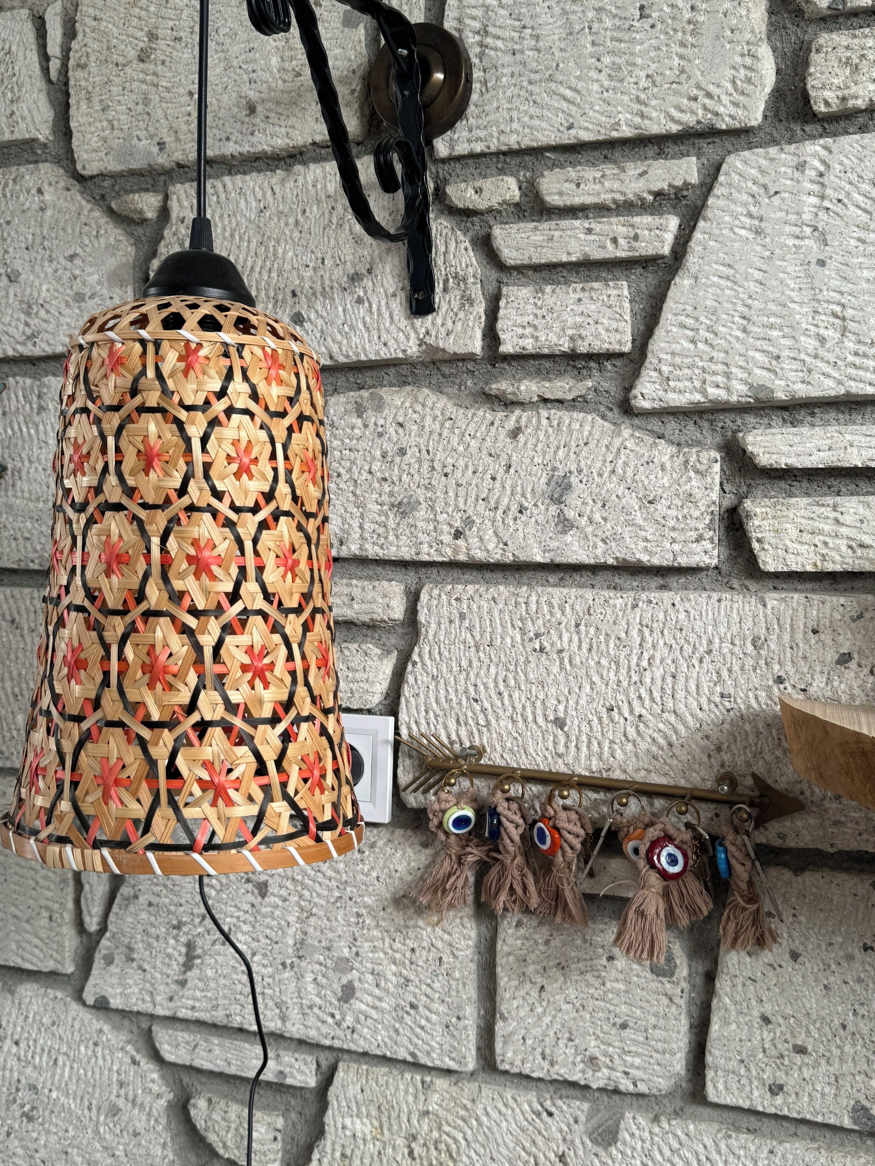 En stenmur med en hängande lampa och dekorativa tofsar.