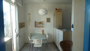 A compact kitchen with a dining table and chairs, a cabinet, and a hanging light fixture. - Vera Cruz A4 (Lido di Jesolo)