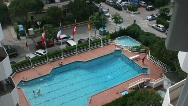 A swimming pool with multiple lanes, surrounded by a fence and flags. - Vera Cruz A4 (Lido di Jesolo)