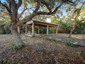A wooden gazebo with benches, surrounded by trees and a grassy area. - Ariel Dunes #1303 | Great Location + Easy Walk to the Sand! (Miramar Beach)