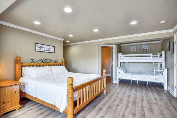 A bedroom with a wooden bed, a bunk bed, a nightstand, and a wall with a motivational quote.