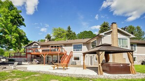 A two-story house with a covered patio, a hot tub, and a fenced deck area.