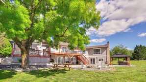 A two-story house with a deck, a gazebo, and a picnic table in the yard.