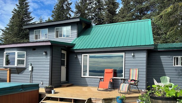 A two-story house with a large deck, a hot tub, and a view of the mountains. - Paradise Suites in Homer Alaska, an entire house w/a hot tub (Homer)