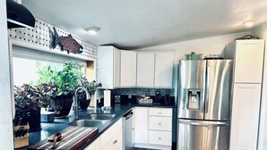 A modern kitchen with white cabinets, stainless steel appliances, and a herringbone wood floor. - Paradise Suites in Homer Alaska, an entire house w/a hot tub (Homer)