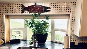 A kitchen with a double sink, a potted plant, and a fish-shaped mosaic above the window. - Paradise Suites in Homer Alaska, an entire house w/a hot tub (Homer)