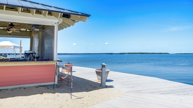 A beachside bar with a pink facade, outdoor seating, and a view of the water.