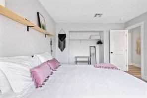 Ein Schlafzimmer mit Bett, Ablagefläche, Tür und Kleiderhaken.
