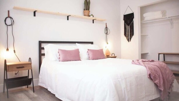 A bedroom with a bed, bedside tables, a hanging plant, and a wardrobe. - 7 Mins to Joshua Tree Park, Hot Tub · Sunset Jewel (Joshua Tree)