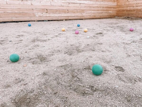 A sandy area with several colorful balls scattered on the ground.