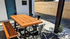 An outdoor dining area with a wooden table and chairs, a bench, and a potted plant. - 7 Mins to Joshua Tree Park, Hot Tub · Sunset Jewel (Joshua Tree)