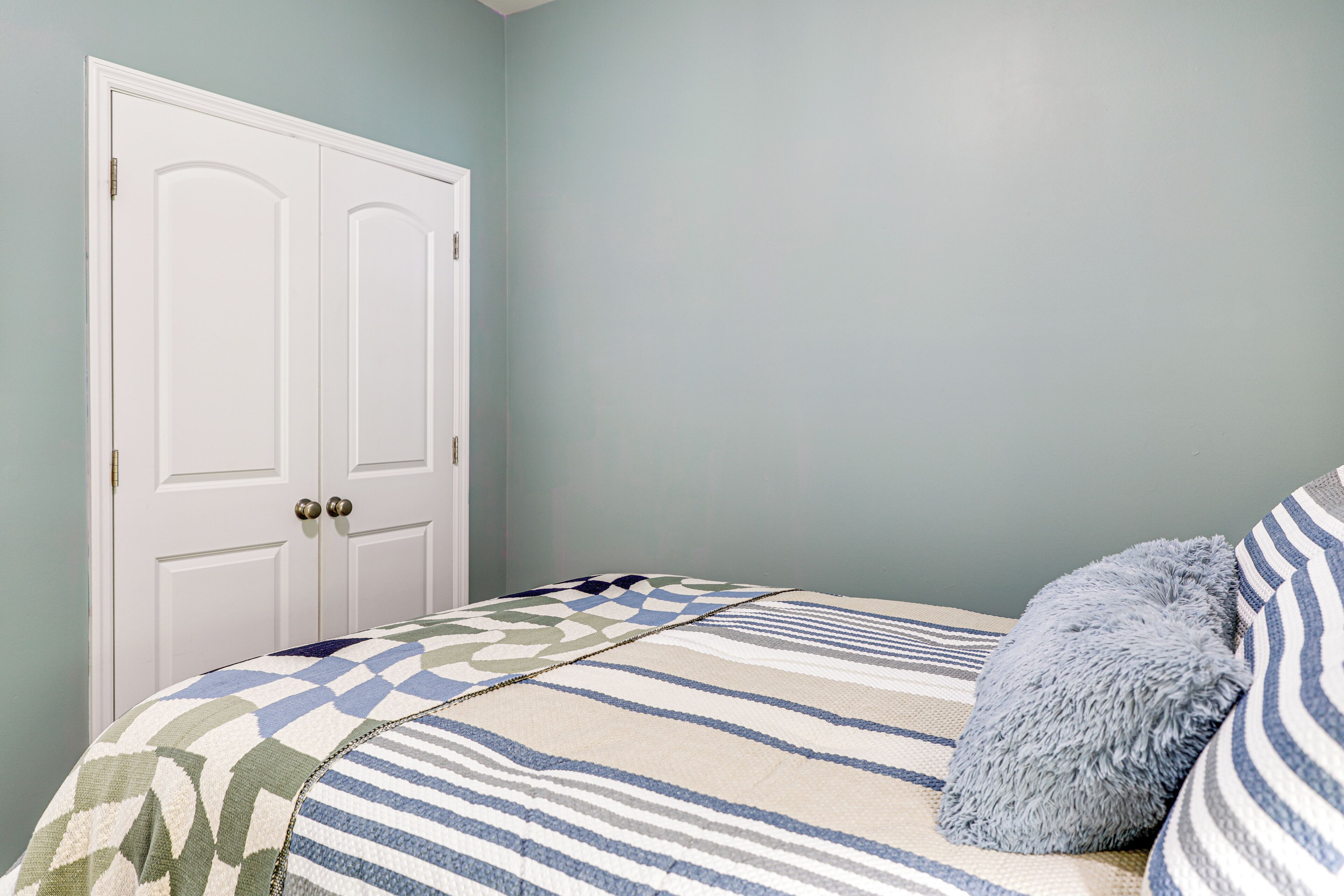 A bedroom with a bed, a door, and a wall.