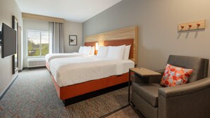 A hotel room with a large bed, a desk, a chair, and a TV mounted on the wall. - Candlewood Suites Oxford - Anniston By IHG (Oxford)