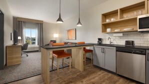 Una cocina moderna con una isla central, taburetes de bar, microondas y lavavajillas.