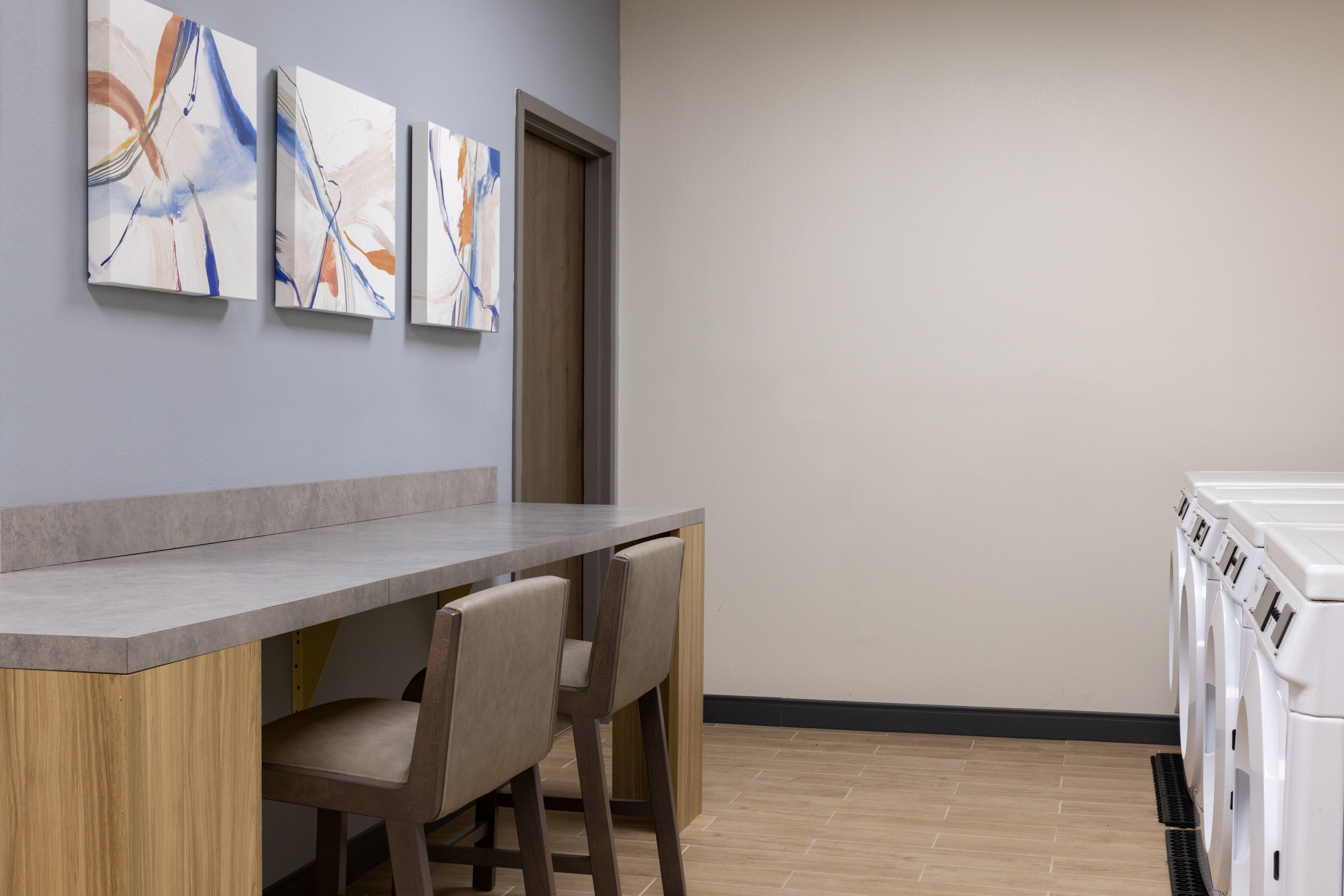 A modern kitchen with a bar area, a washing machine, and abstract art on the wall.