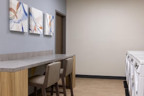 Una cocina moderna con barra, lavadora y arte abstracto en la pared.