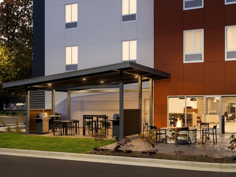 A modern building with a covered outdoor seating area, a barbecue grill, and a fire pit.