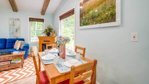 Ein Essbereich mit einem Holztisch, gedeckt für vier Personen, einem blauen Sofa und einem Kamin.