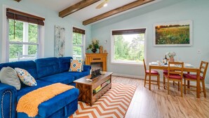 Ein Wohnzimmer mit einem blauen Sofa, einem Holzesstisch und einem Teppich mit Zickzackmuster.