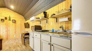 Una cocina con paredes de madera, microondas, lavaplatos y refrigerador.