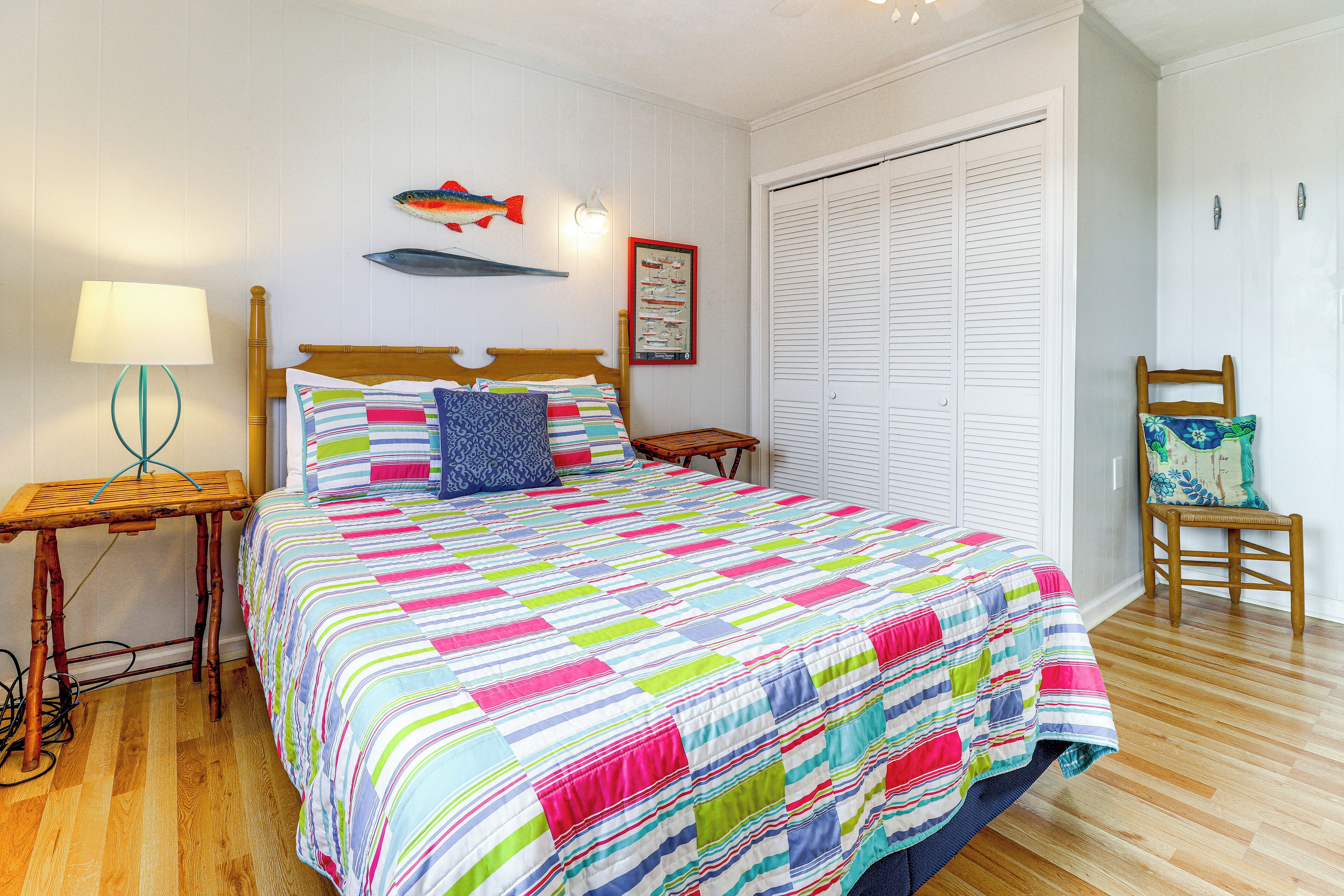 A bedroom with a wooden bed, a nightstand, a chair, a wall-mounted fish decoration, and a framed menu on the wall.