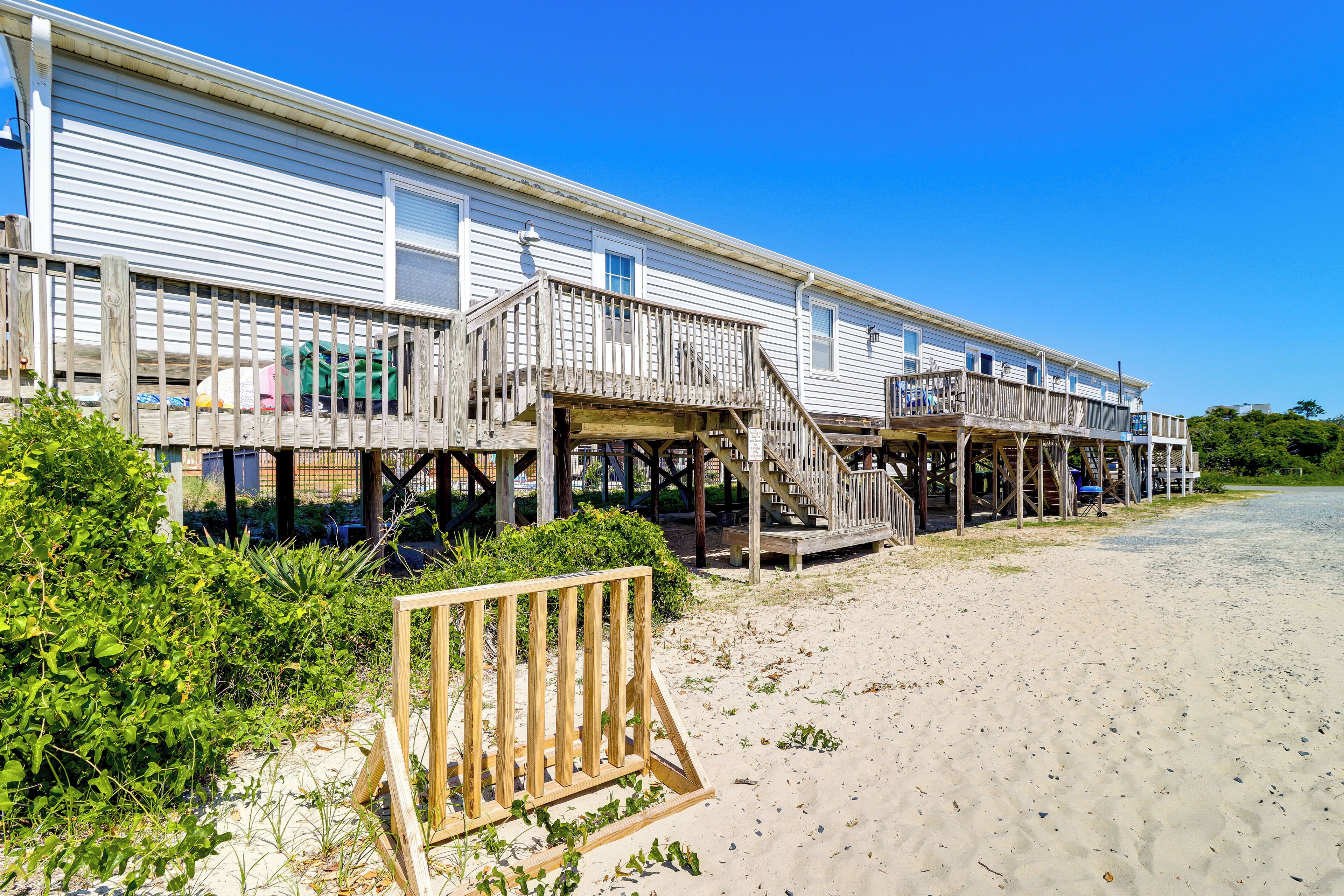 A beachfront wooden structure with multiple decks and a sandy beach in the foreground.