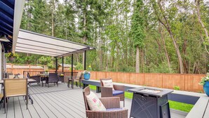 Eine Terrasse mit Gartenmöbeln, einer Feuerstelle und einer Pergola.