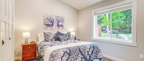 A bedroom with a large bed, a nightstand with a lamp, and two wall-mounted paintings of deer.