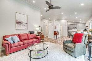 A modern living room with a red leather sofa, a glass coffee table, and a grey armchair. - Freeland Retreat - Deck, Fire Pit & Beach Access! (Freeland)