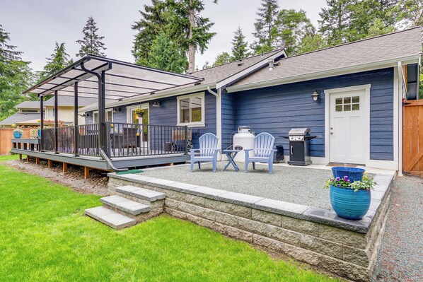 A house with a covered patio, two chairs, a grill, and a large planter. - Freeland Retreat - Deck, Fire Pit & Beach Access! (Freeland)